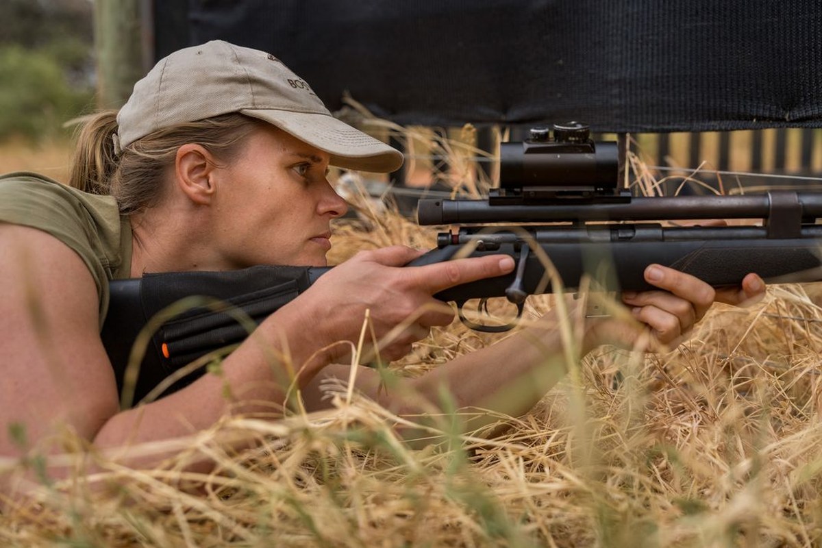 Jana Pauwels, a veterinarian working with the Endangered Wildlife Trust, positions herself to tranquilize an African wild dog in an enclosure.
