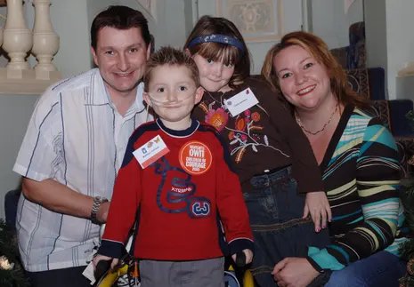 A family photograph of a father, mother, a little girl and a boy with tubes in his face