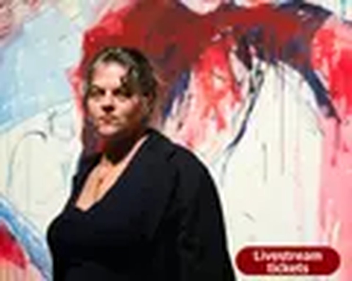 Tracey Emin stands in front of a large red, blue, and white abstract painting with bold, gestural brushstrokes and drips. She wears a black outfit and a gold necklace, facing the camera with a serious, direct expression.