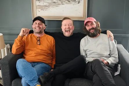 Three men sitting on a sofa laughing