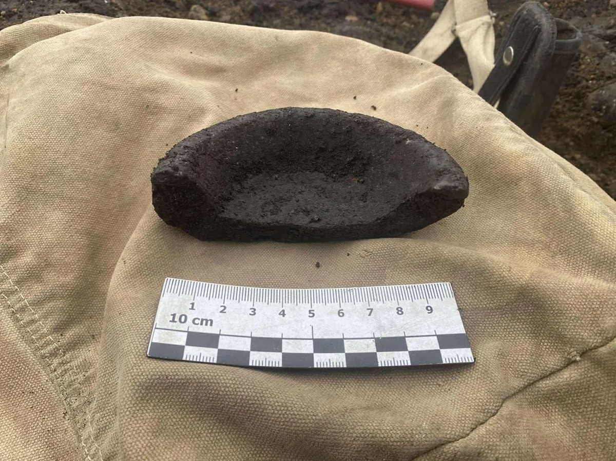 Half a broken piece of soapstone next to a little ruler