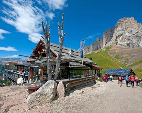 People walking next to the refuge, with a mountain peak in the background