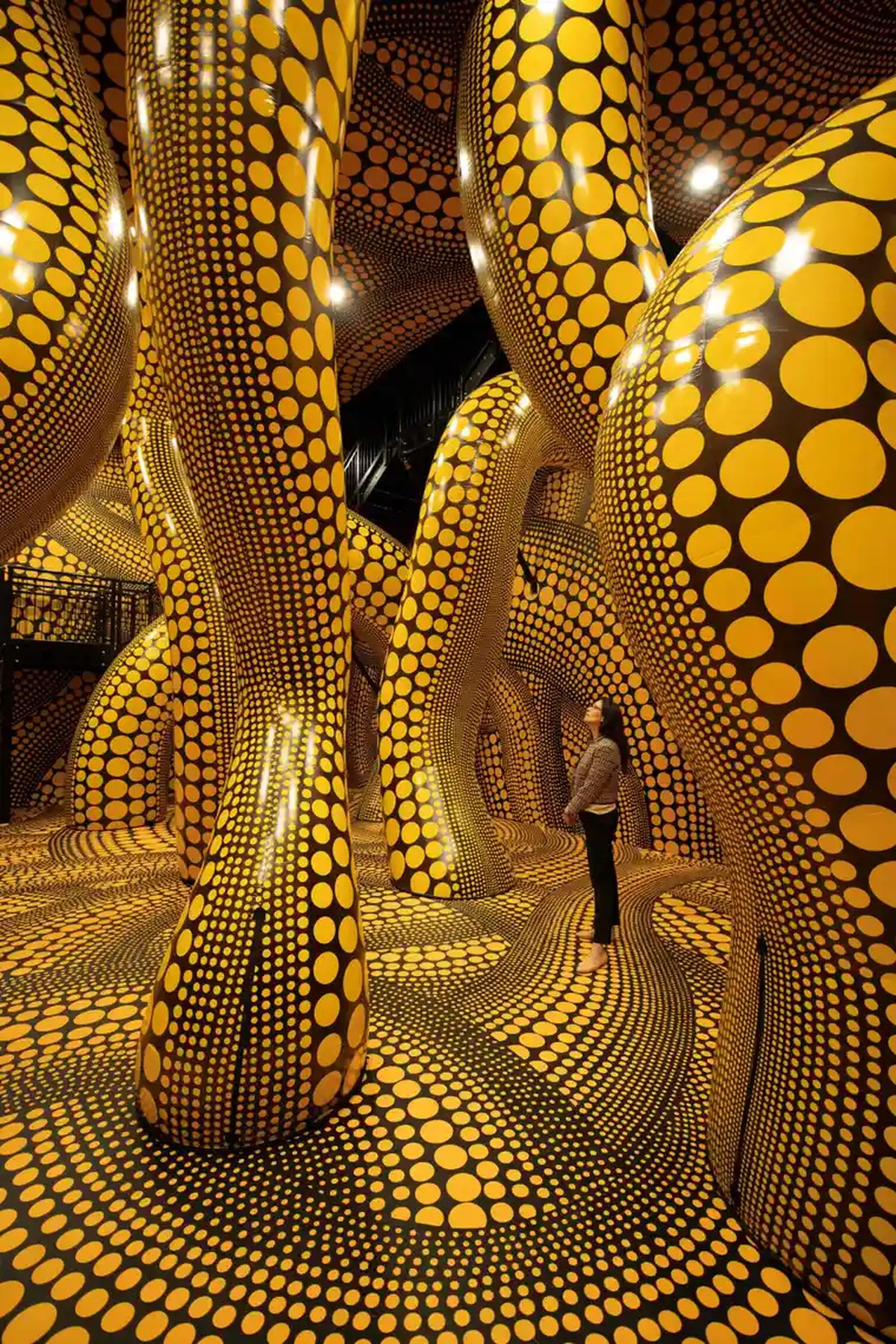 A woman admires The Hope of the Polka Dots Buried in Infinity Will Eternally Cover the Universe by Yayoi Kusama at Aviva Studios, Manchester.