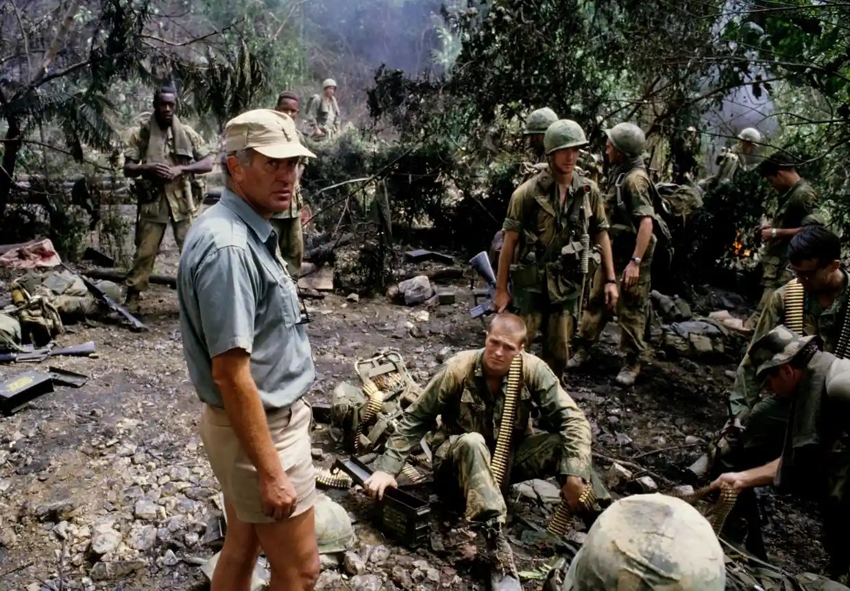John Irvin surrounded by actors in fatigues