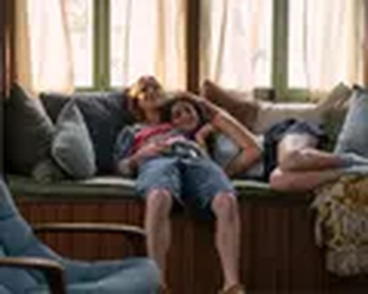 Oona and Annie lie together on a cozy window bench, one resting her head on the other's lap