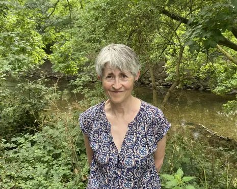 Helen Harris in front of a river running through woodland
