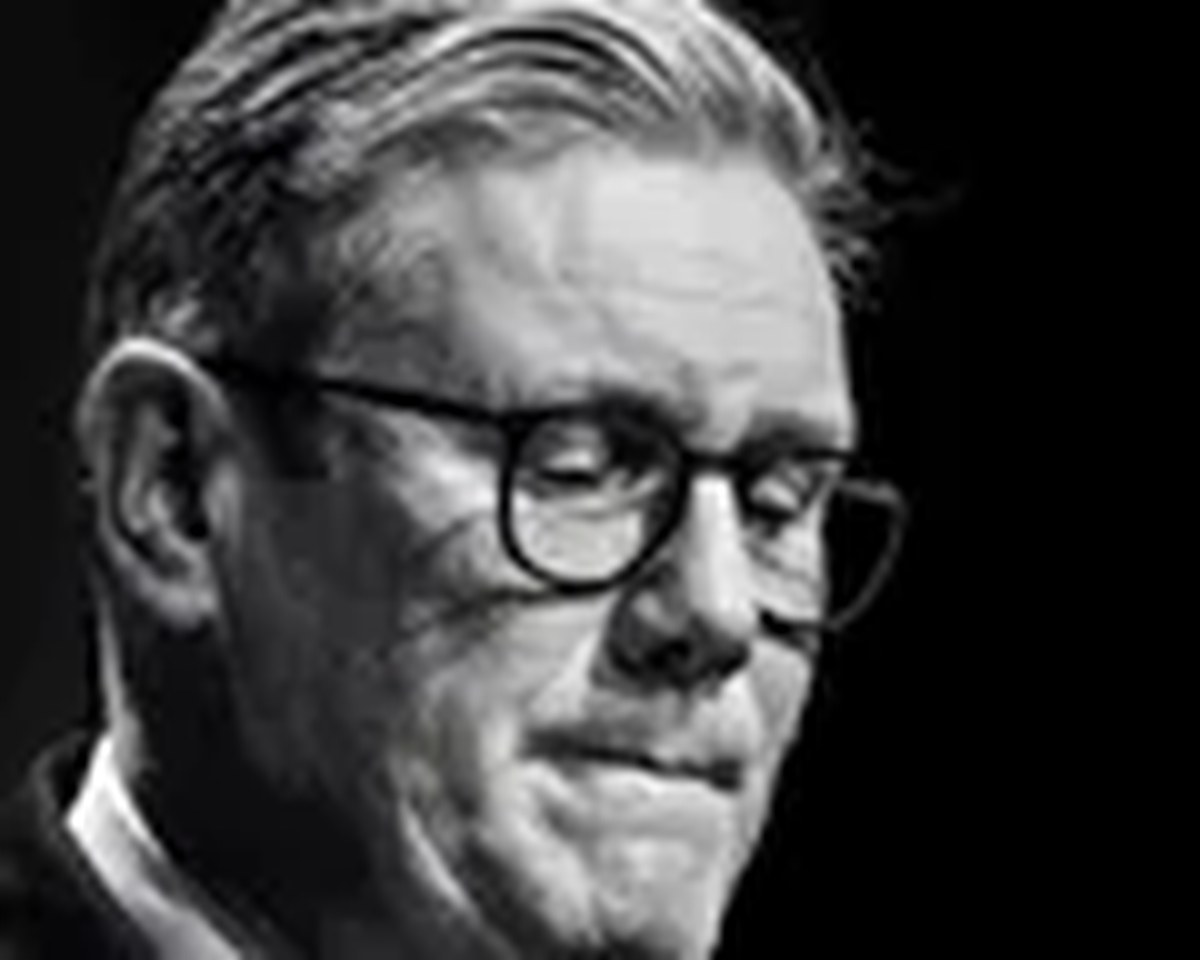 Black-and-white close-up portrait of a man wearing glasses, looking down sollumnly.