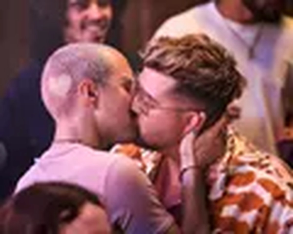 Gay couple embracing amongst a crowd of people.Kissing on a crowded dance floor .