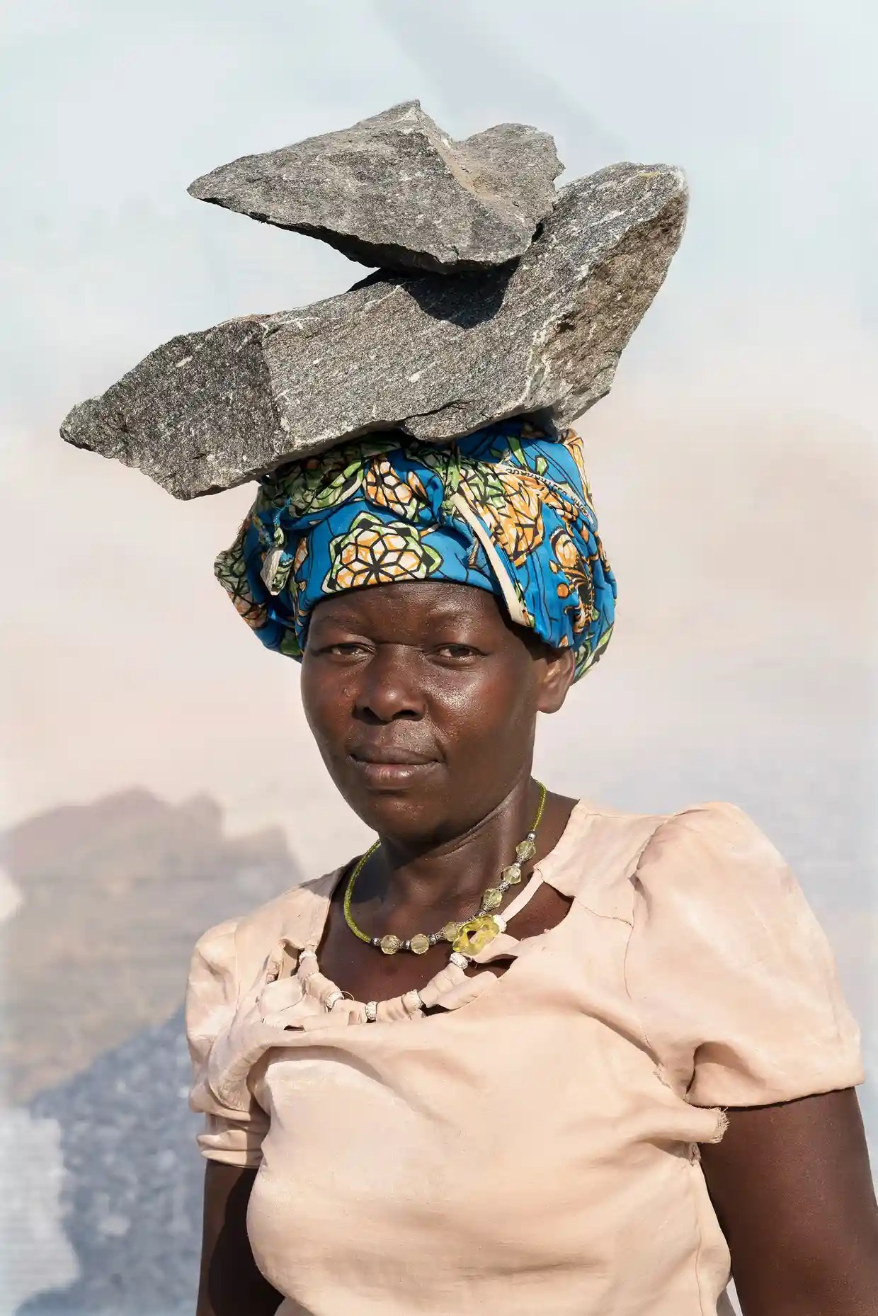 Janet, a quarry worker, balances a large stone slab on her head
