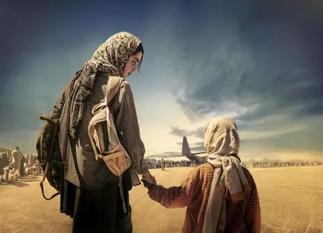A woman in a headscarf holding a child's hand, with the desert in front of them