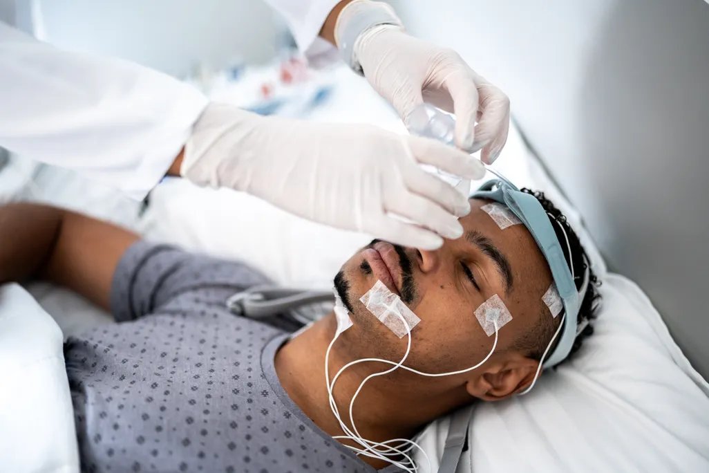 person with electrodes on their head doing a sleep study