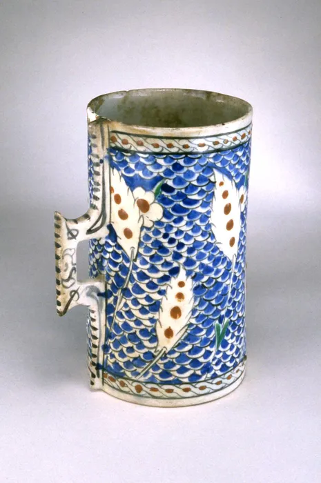 Vessel (humpen-shaped), tankard. Hastate saz leaves and prunus blossoms reserved on scale ground.Handle has stylised stitching. Made of black, turquoise, cobalt, red (bole) painted and glazed ceramic, pottery. - Bilinmiyor