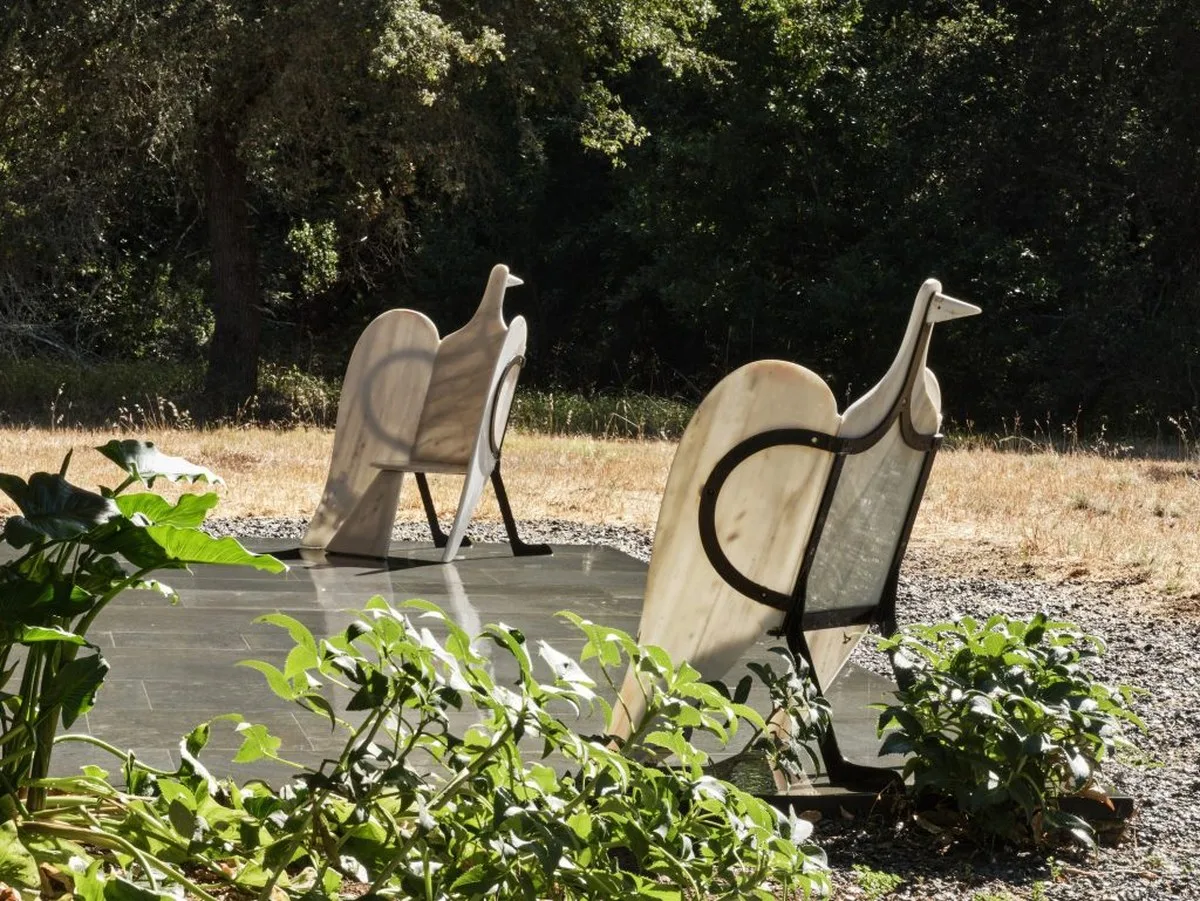 a pair of armchairs in a garden with sunshine and greenery