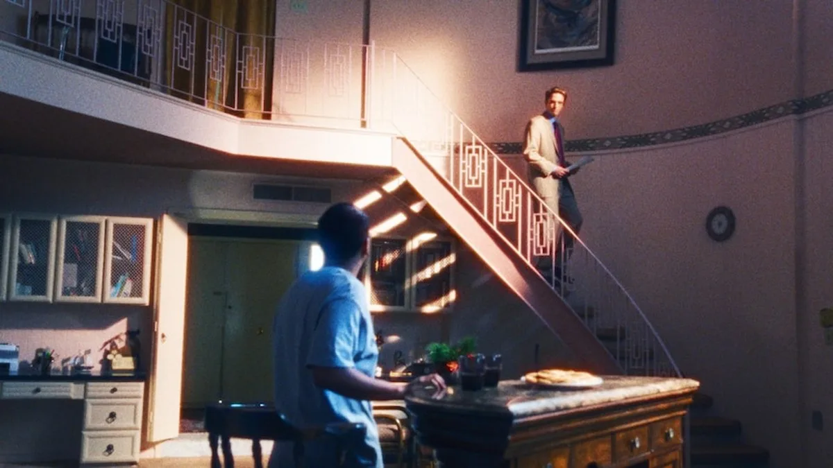 A man walks down stairs in a lounge room to another man