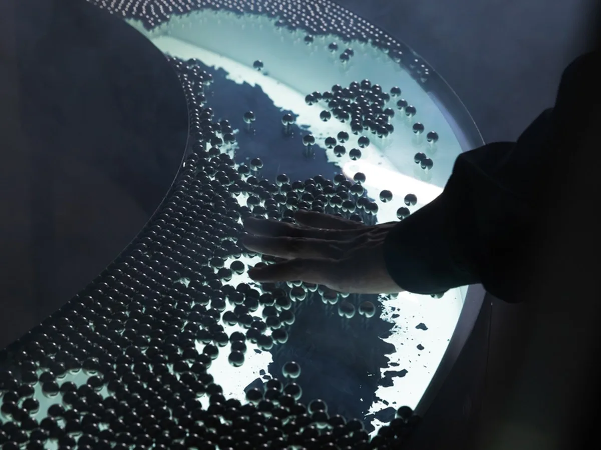 steel spheres moving across curved glass frame leonardo garza’s sensory installation for BYREDO - 2